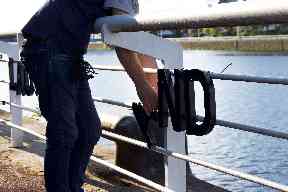 Helping hand: Ahmad threads the letters onto the railings.