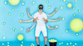 A blindfolded Andre Ortolf demonstrates bouncing tennis balls and catching them.