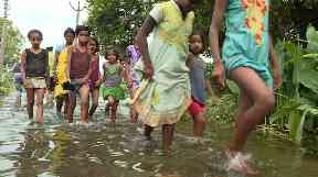 Children paddle through floodwaters in India.