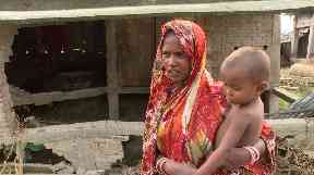 Farida Begaum stands in front of her ruined home.