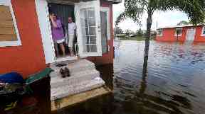 A Florida family looks on as their home is surrounded by flood water.