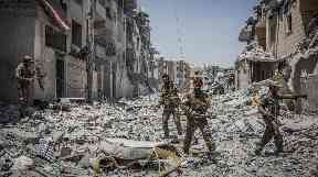 SDF soldiers move through debris in the Al Dariya neighborhood in western Raqqa