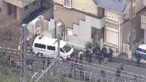 Media gather outside the suspect's home where dismembered bodies were found.