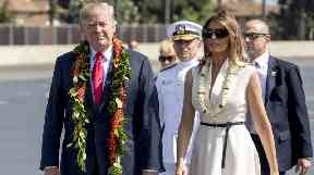 President Donald Trump and first lady Melania Trump wear leis as they arrive at Joint Base Pearl Harbor Hickam, Hawaii.