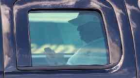 Donald Trump uses his phone inside an armoured presidential vehicle.