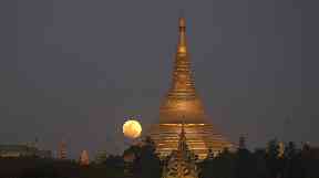 The moon rises behind Myanmar landmark Shwedagon pagoda.
