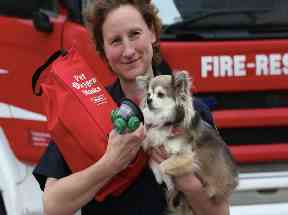 A fire officer demonstrates a pet sized oxygen mask on a dog