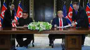 Kim Jong-un and Donald Trump make history as they sign an unspecified document.