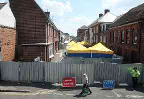 A police officer stands in front of screens erected in Rollestone Street, Salisbury
