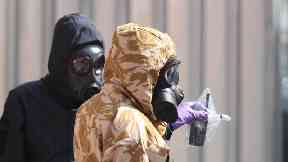 Investigators in chemical suits remove an item as they work behind screens erected in Rollestone Street, Salisbury