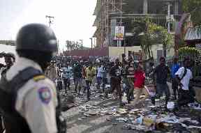 A crowd enters the Delimart supermarket complex, which was burned during the protests