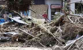 A man cleans debris caused by heavy rain in Soja, Okayama prefectur
