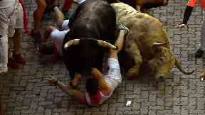 Revellers fall next to fighting bulls in Pamplona.