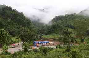 Rescuers stand at a checkpoint near the entrance to the cave