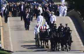 Family members, including Cindy McCain, follow the horse-drawn carriage