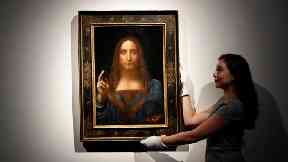 An employee poses with Leonardo da Vinci’s Salvator Mundi.