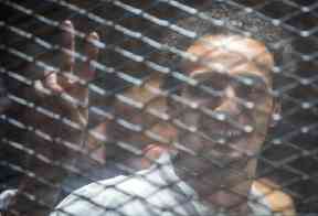 Mahmoud Abu Zaid smiles inside a cage in the Cairo court