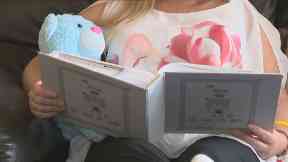 Laura is comforted by a blue bear containing her son's ashes.