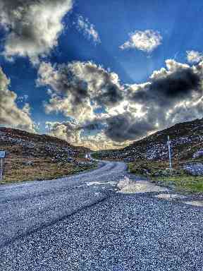 Striking clouds rumble over a winding road.