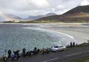 Bikers stop for a rest near the white sandy beach.